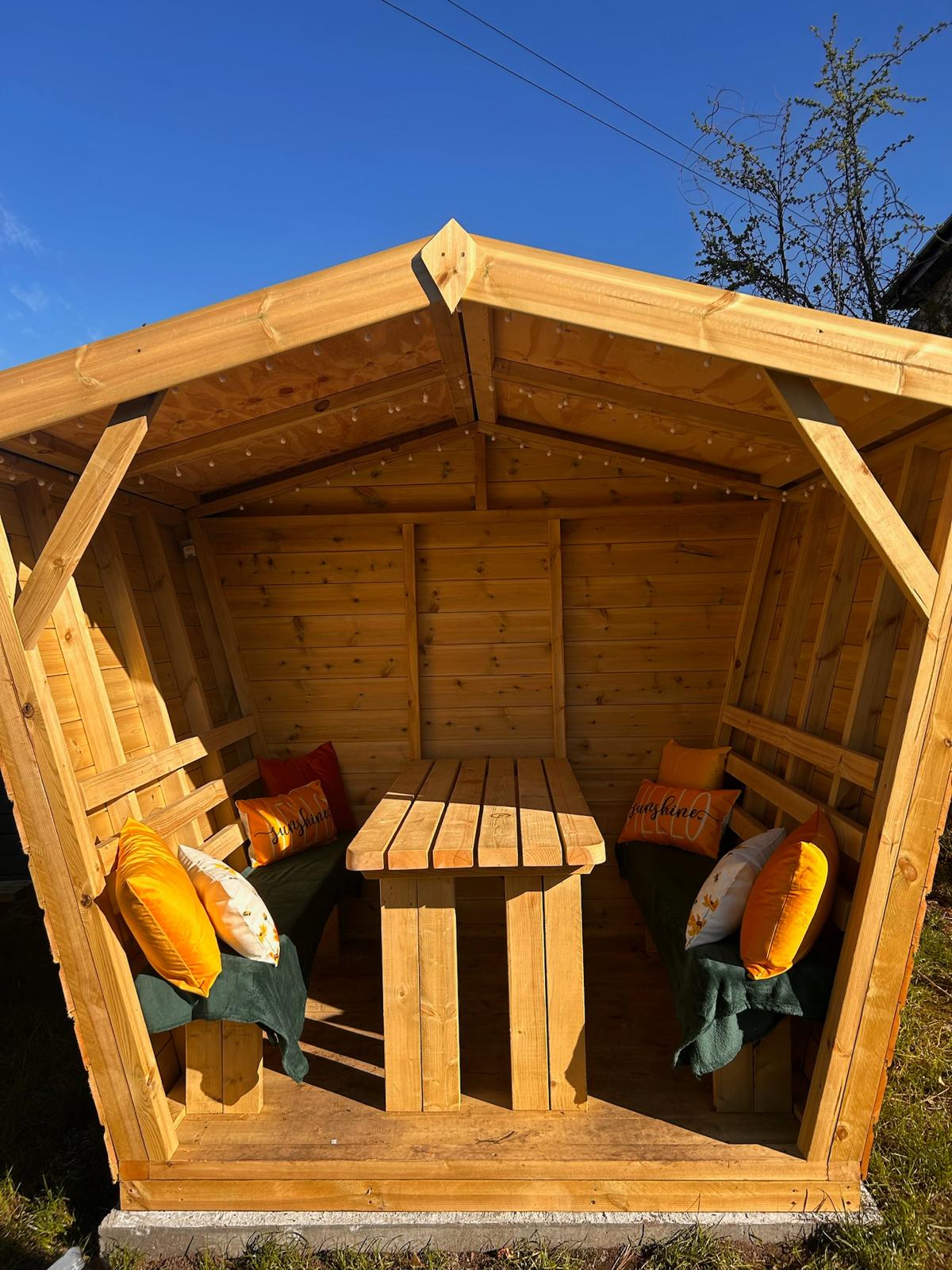 The wooden snug seating pod with cushions in the beer garden